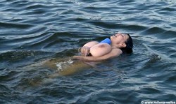 Dark-haired MILF enjoys being topless in the ocean