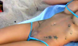 The hottest tattooed brunette in blue bikinis reveals a pierced pussy