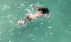 Slender long-legged brunette spotted topless on the beach