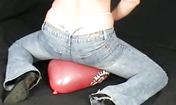 Sexy as hell lady in blue jeans is jumping on a red balloon