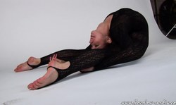 Crazy flexible gymnast in black suit poses on a white background